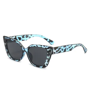 Blaue Cat-Eye-Sonnenbrille mit Kuhmuster und dunklen Gläsern für stilvollen Sonnenschutz.