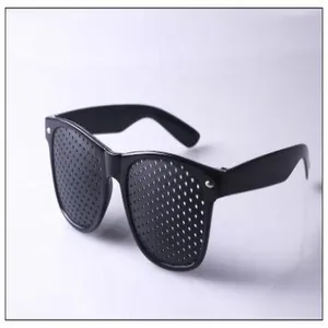 Detail view of black pinhole glasses with plastic frame on white reflective background