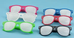 Assorted multi-colored plastic pinhole glasses with mesh lenses on a blue surface