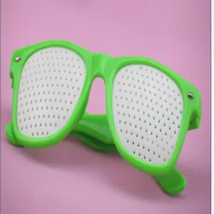 Detailed close-up view of green vision training pinhole glasses with white plastic lenses