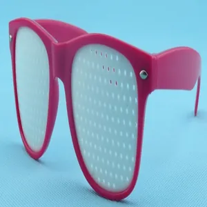 Close-up of pink pinhole glasses with white stenoic lenses on blue background