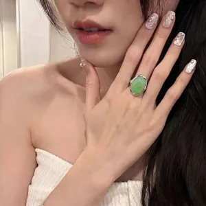 Detailaufnahme eines luxuriösen grünen ovalen Edelsteinrings an einem Modellfinger.