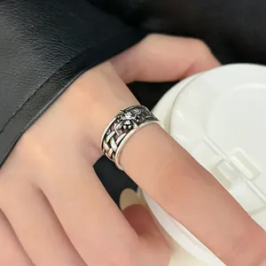 Detailed close-up view of a vintage silver floral open ring styled with black leather