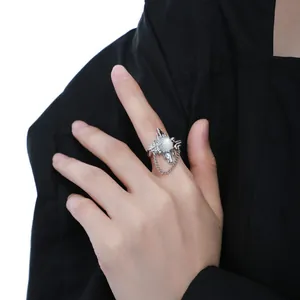 Detailed view of a silver ring with moonstone and chain worn on the index finger.