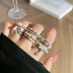 Detailansicht von geschichteten französischen Barock-Perlenringen mit Strass an der Hand.