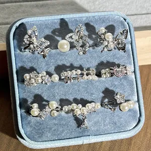 Kollektion von neun eleganten Perlen- und Zirkonringen in einer blauen Samtbox