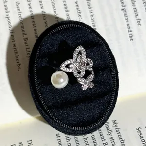 Detailansicht eines eleganten Schmetterlings- und Perlenrings in einer schwarzen Schatulle.