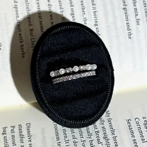 Detailansicht von stapelbaren Barockperlen- und Kristallringen in einer Box.