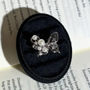Detailaufnahme eines silbernen Schmetterlingsrings mit Perlen in einer schwarzen Box.