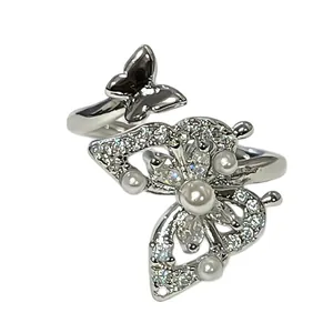 Eleganter silberner Schmetterlingsring mit weißen Perlen und funkelnden Kristallen in Detailansicht