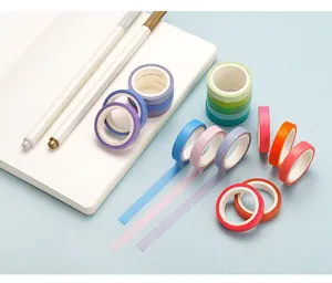 Close-up of colorful rainbow washi tapes arranged on a desk with a white notebook and pens