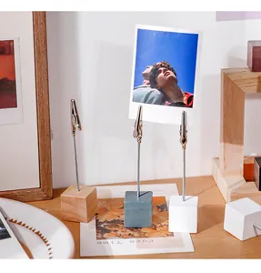Lifestyle detail of wooden base photo clips holding a polaroid picture on a desk