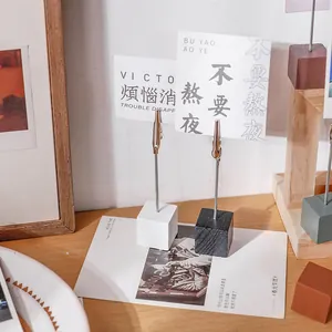 Wooden cube base photo holder with metal alligator clip for desktop notes and memos.