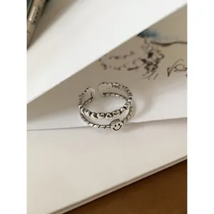 Macro detail of vintage Thai silver ring featuring heart patterns and a smiley face.