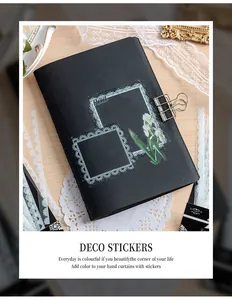 Detail van witte kant PET-stickers aangebracht op een zwart DIY-plakboekomslag