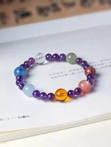 Close-up of a natural multi-gemstone bracelet with amethyst and aquamarine on a book