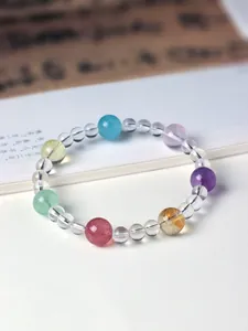 Close-up detail of a handmade multi-color natural gemstone bracelet on white paper.