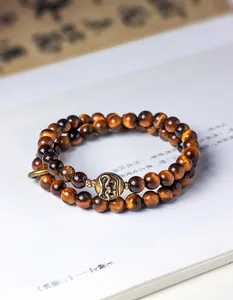 Detail view of double-wrap tiger eye beaded bracelet with antique bronze charm