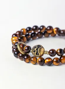 Close-up macro view of polished yellow tiger's eye beads with ornate Tibetan bronze charm