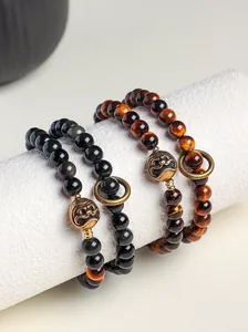 Close-up of Tiger's eye and obsidian beaded bracelets with bronze accents.
