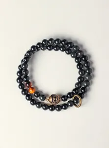 Macro detail of double-layer obsidian bracelet with bronze accent and tiger eye beads