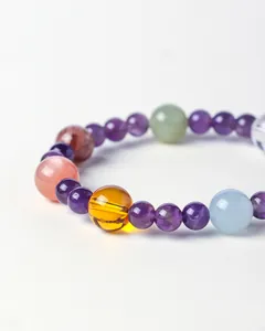Close-up detail of a natural multi-gemstone bracelet with amethyst and amber beads.