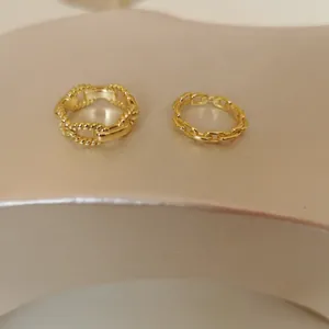 Detailed view of two minimalist gold-plated silver chain rings with link designs.