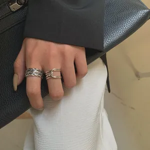 Close-up detail of retro Thai silver braided band and cross open ring on finger