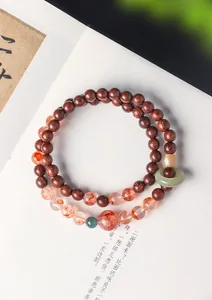 Close-up detail van bloedsandelhout en rode kwarts dubbelstrengs armband met jade ring
