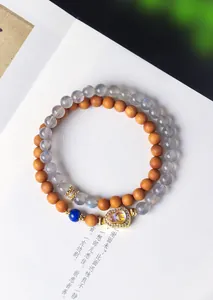 Detailopname van dubbelstrengs sandelhout en labradoriet kralenarmband met een kristallen hulu-hanger