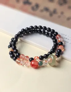 Detail van een dubbelstrengs armband met zwart sandelhout en rode fantoomkwartskralen