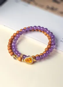 Detailopname van dubbellaagse armband met amethist, sandelhout kralen en kalebas hanger.