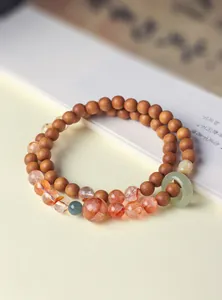 Macro detail van een dubbelstrengs sandelhout armband met rood kwarts en jade ring