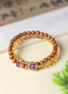 Detailopname van sandelhout en amethist kralenarmband met paarse kalebas bedel