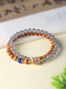 Detail van een dubbele kralenarmband met sandelhout kralen en een gouden kalebas