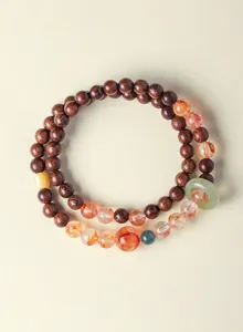 Elegante dubbele kralenarmband met sandelhout, rood fantoomkwarts en jade ring detail.