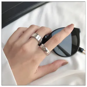 Detailed shot of two minimalist 925 sterling silver rings on hand with sunglasses.