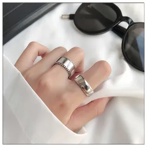 Close-up of wide 925 sterling silver rings showing polished and milgrain textures.