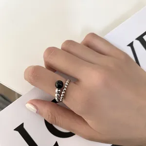 Close-up detail of a minimalist silver beaded ring with a black gemstone accent