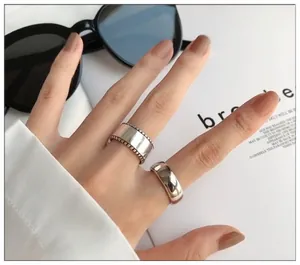 Close-up of chunky 925 sterling silver rings with polished and beaded edges on a hand.