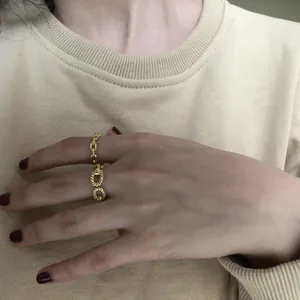 Close-up view of a minimalist gold pig nose chain ring worn on a woman's finger