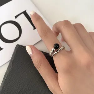 Close-up of a 925 sterling silver woven ring with a black gemstone on an Asian hand.