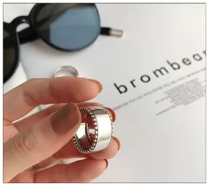 Close-up view of a minimalist S925 sterling silver wide band ring with beaded edges