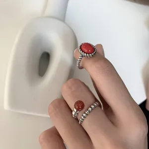 Detail of 925 sterling silver rings with red gemstones on a minimalist background.