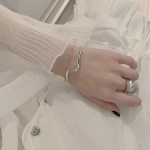 Minimalistische S925 sterling zilveren golvende open armband op pols met geplooide achtergrond