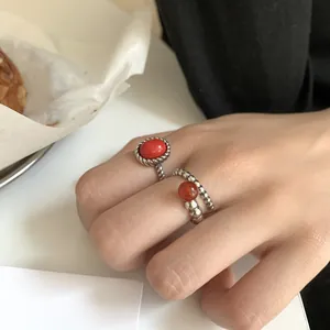 Close-up of hand wearing two distinct 925 sterling silver rings set with red gemstones