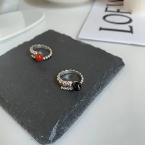 Detailed view of sterling silver beaded rings with red and black round stones on slate