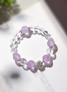 Primer plano de pulsera de amatista lavanda y cristal con colgantes de flor de loto
