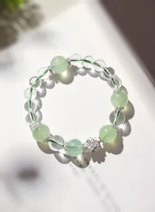 Primer plano de una pulsera de cuentas de cuarzo transparente y prehnita verde con loto