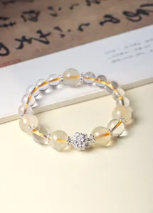Detalle macro de pulsera de cuentas de cristal transparente y amarillo con loto de plata